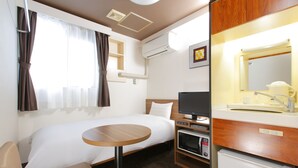Habitación de hotel con cama, una mesita, televisor, microondas y lavamanos con espejo.