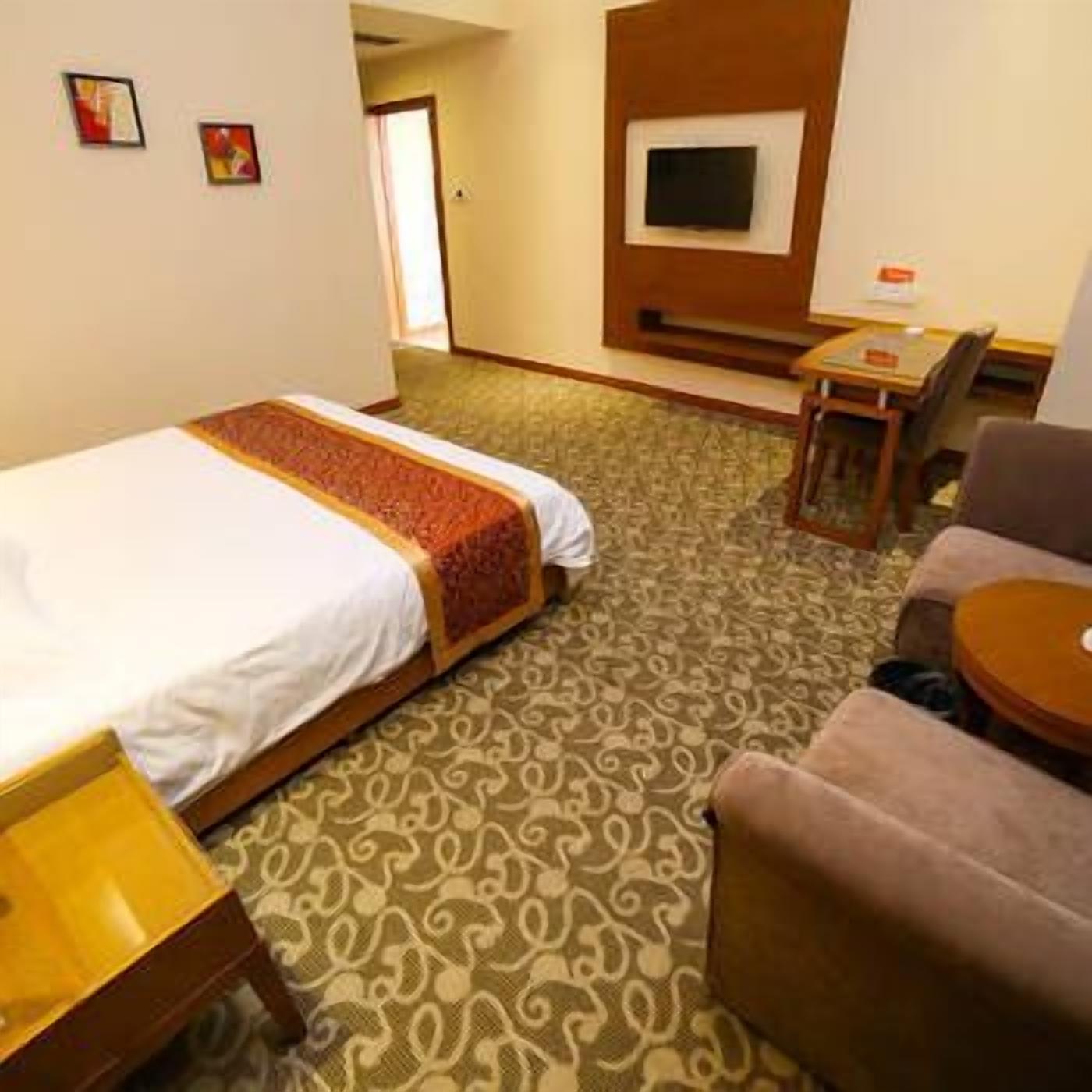 A hotel room with a bed, a desk, a chair, and a television.