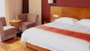 Une chambre d’hôtel avec un lit double, une petite table ronde, un canapé et une lampe fixée au mur.