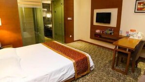 Une chambre d’hôtel équipée d’un lit, d’un bureau, d’une télévision et d’une porte donnant accès à une salle de bain.