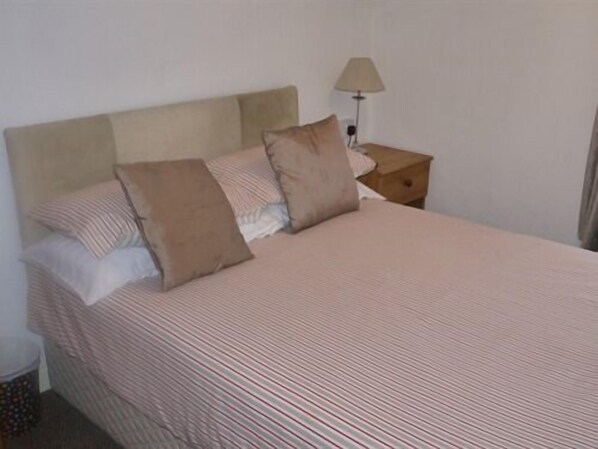 A neatly made bed with striped bedding and two pillows. - Hazelgrove Guest House (Blackpool)