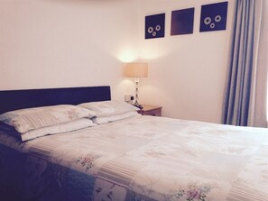 A neatly made bed with floral bedding, a bedside lamp, and a wall with three circular wall art pieces. - Hazelgrove Guest House (Blackpool)