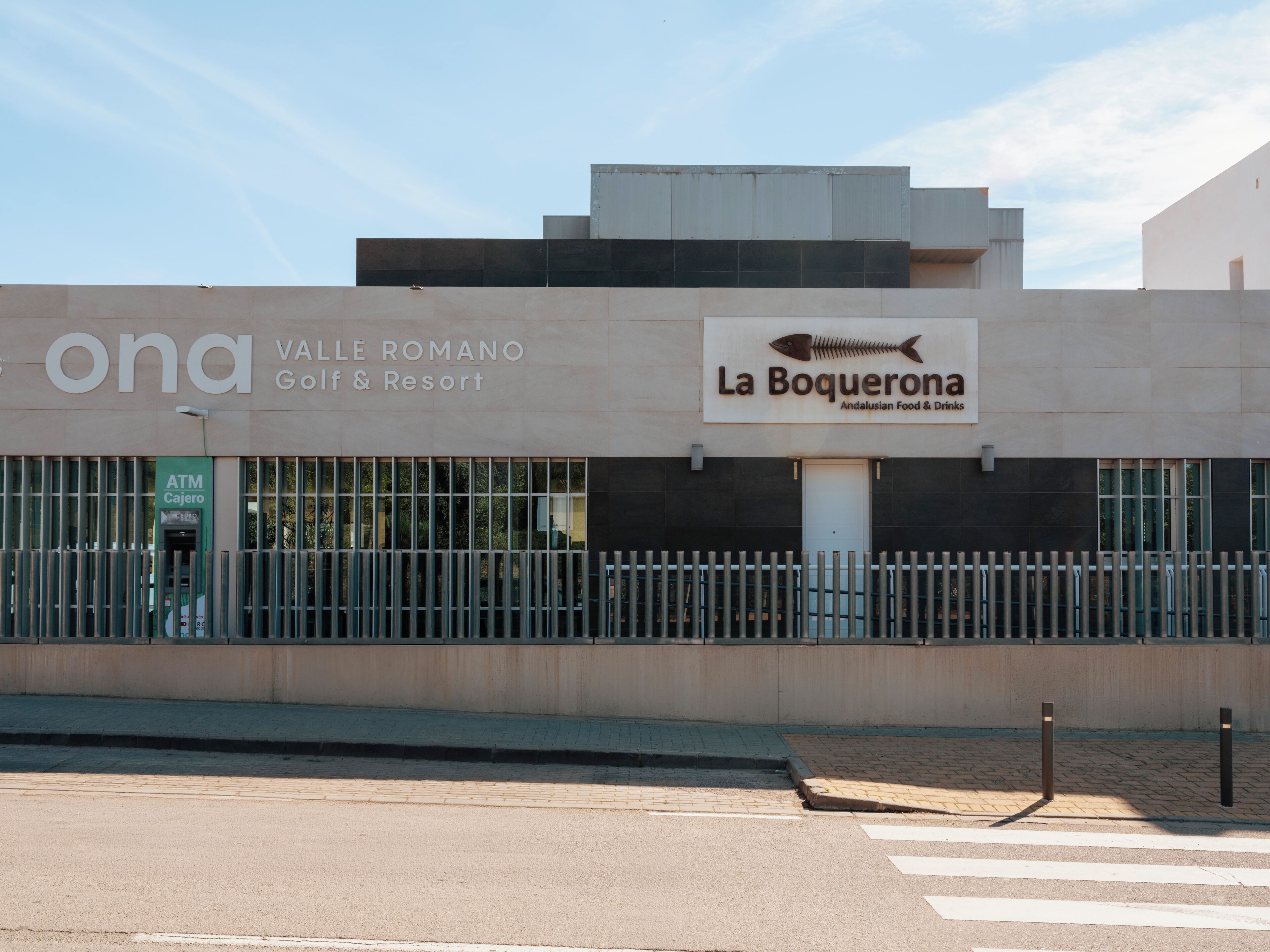Un edificio con letreros que indican 'VALLÉ ROMANO Golf & Resort' y 'La Boquerona Andalusian Food & Drinks'.
