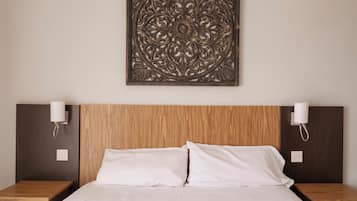 A hotel room with a wooden headboard, two bedside tables with lamps, and a decorative wall piece above the bed.