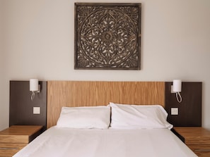 A hotel room with a wooden headboard, two bedside tables with lamps, and a decorative wall piece above the bed. - Ona Valle Romano Golf & Resort (Estepona)