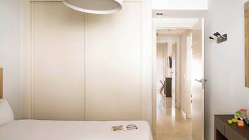 Una habitación de hotel con una cama, una mesita de noche, un armario y una puerta que da a otra estancia.