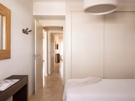 A bedroom with a bed, a bedside table, a mirror, and a wardrobe.