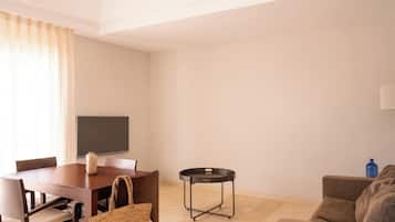 Un comedor con mesa, sillas, televisor, una mesita redonda y un sofá.