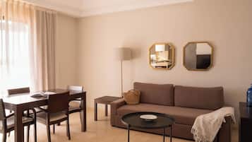 A living room with a sofa, a coffee table, a dining table with chairs, and a lamp.