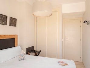 A bedroom with a bed, a chair, a lamp, and a door. - Ona Valle Romano Golf & Resort (Estepona)