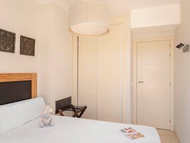 Ein Schlafzimmer mit einem Bett, einem Sessel, einer Lampe und einer Tür.
