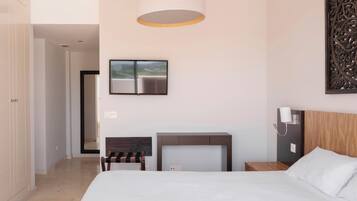 Una habitación de hotel moderna con una cama grande, un televisor de pantalla plana, un cabecero de madera, una mesita de noche y un adorno en la pared.