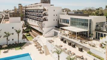 Un hotel con varias plantas, zonas de estar al aire libre y una piscina.