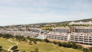 A modern residential complex with multiple apartment buildings, a central courtyard with a pool, and surrounding greenery. - Ona Valle Romano Golf & Resort (Estepona)