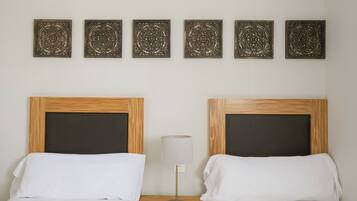 Una habitación de hotel con dos camas, una mesita de noche, una lámpara y decoración mural.