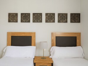 Een hotelkamer met twee bedden, een nachtkastje, een lamp en decoratieve wanddecoratie.