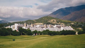 A hotel with a flat roof and multiple stories, surrounded by greenery and mountains. - Ona Valle Romano Golf & Resort (Estepona)