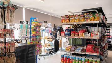 Interior de una tienda con diversos productos en las estanterías, como aperitivos y bebidas.
