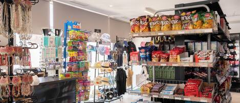 Interior de una tienda con diversos productos en las estanterías, como aperitivos y bebidas.