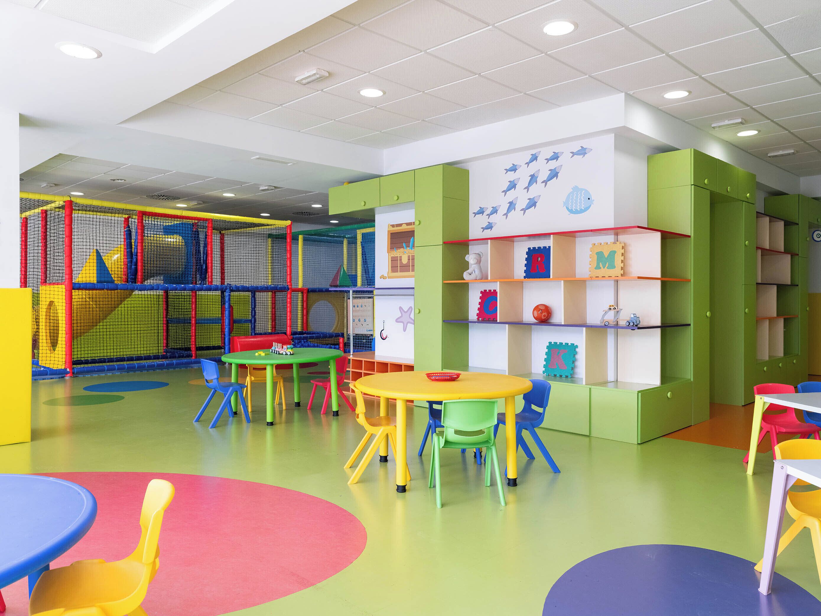 Un área de juegos infantiles con estructuras coloridas, mesas y sillas.