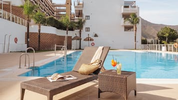 Una piscina al aire libre de temporada, sillones reclinables de piscina