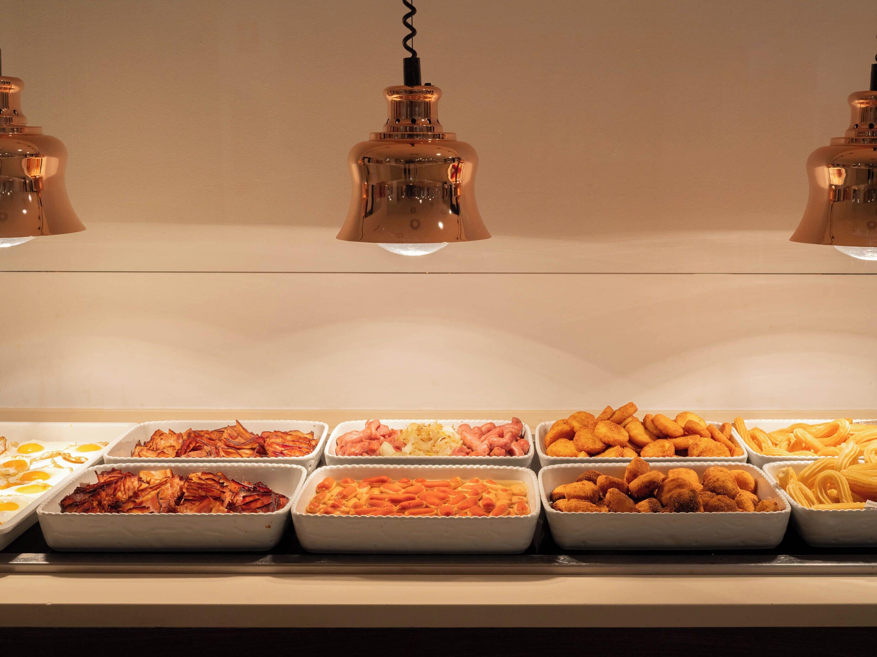 Un buffet proposant une variété de plats, notamment des œufs, de la viande et des pâtes.