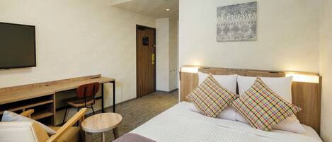 Una habitación de hotel con cama, escritorio, silla, televisor y puerta.