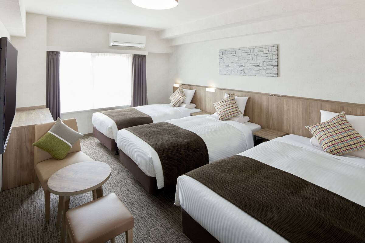 Una habitación de hotel con dos camas, un escritorio y una silla.