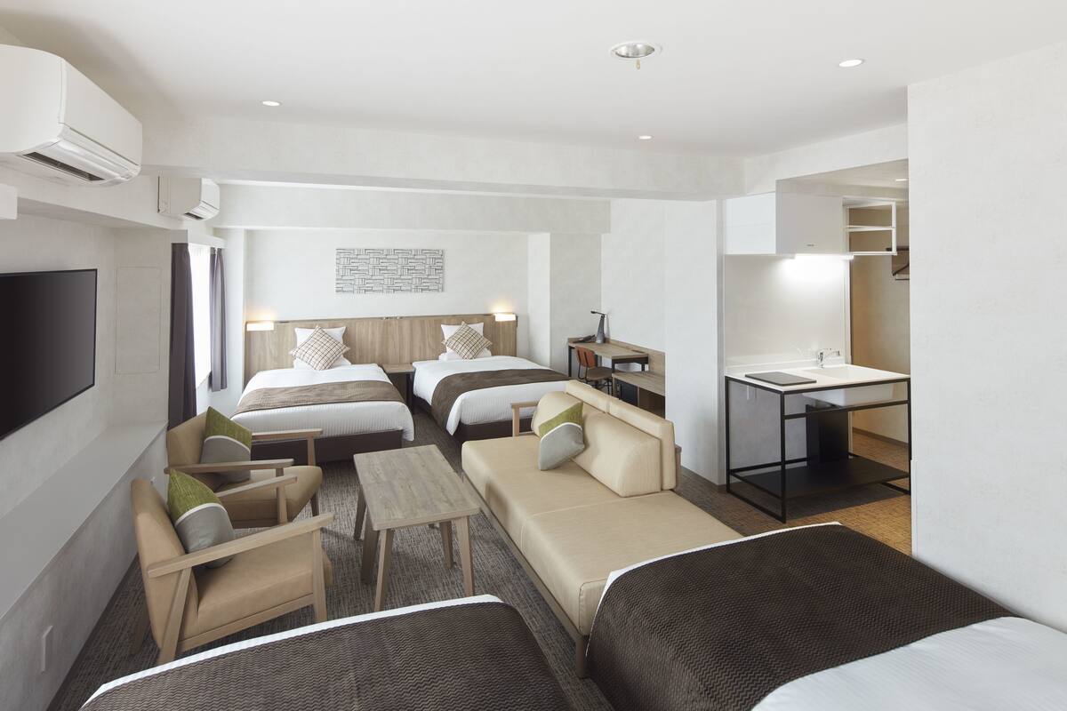 Una habitación de hotel moderna con dos camas, un sofá, un escritorio y un televisor.