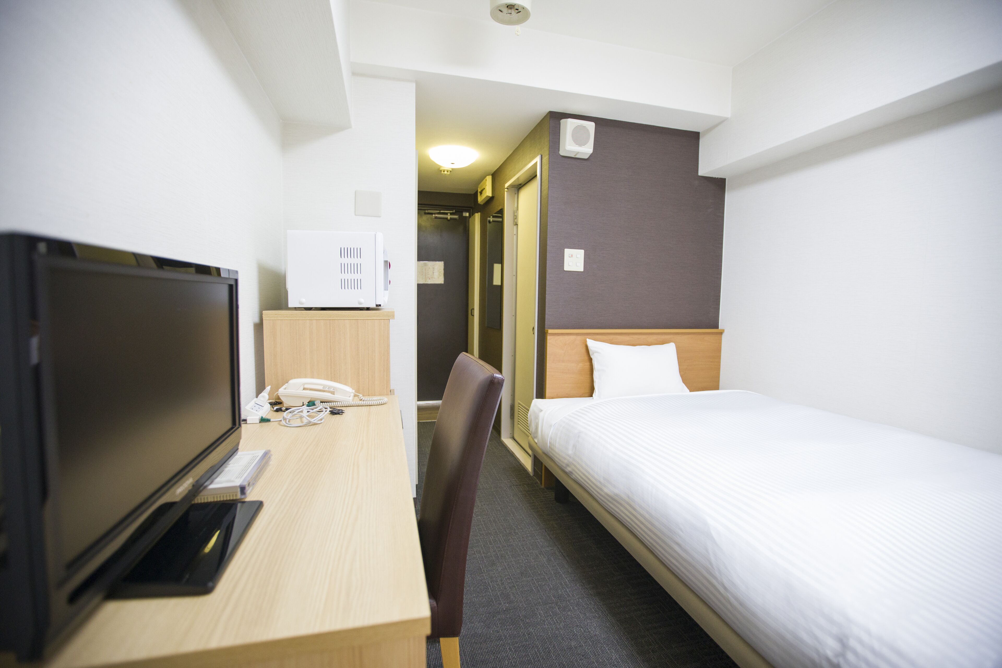 Habitación de hotel con cama, escritorio con ordenador, silla y televisión.