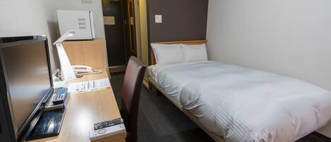 A hotel room with a bed, a desk with a computer, a chair, and a television.