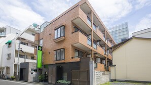 A multi-story building with a brick facade, large windows, and a balcony on the upper floors. - Flexstay Inn Shirogane (Tokyo)