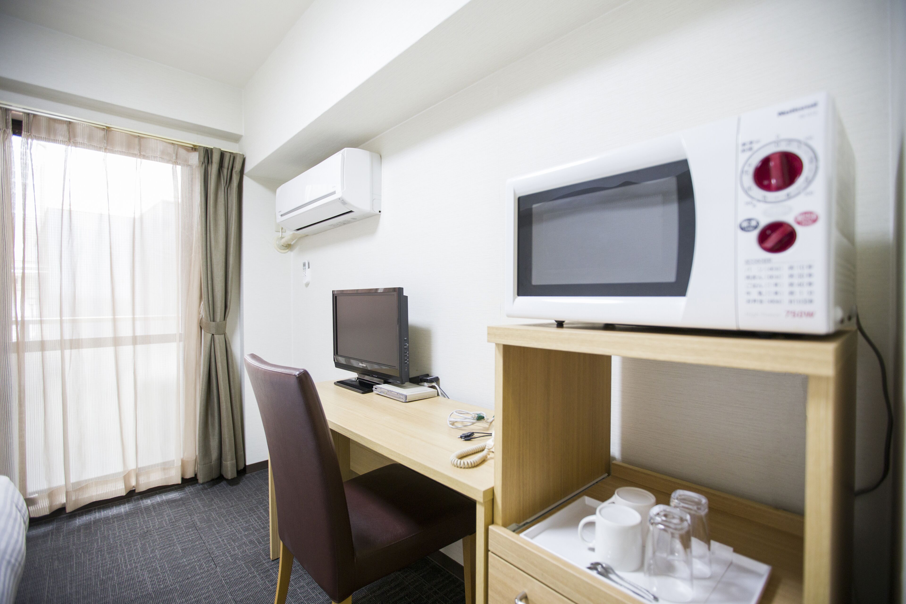 Una camera d'albergo con una scrivania, un computer, un forno a microonde e un minibar.