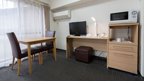 A hotel room with a wooden desk, a television, a microwave, a small cabinet, and a window with sheer curtains. - Flexstay Inn Shirogane (Tokyo)