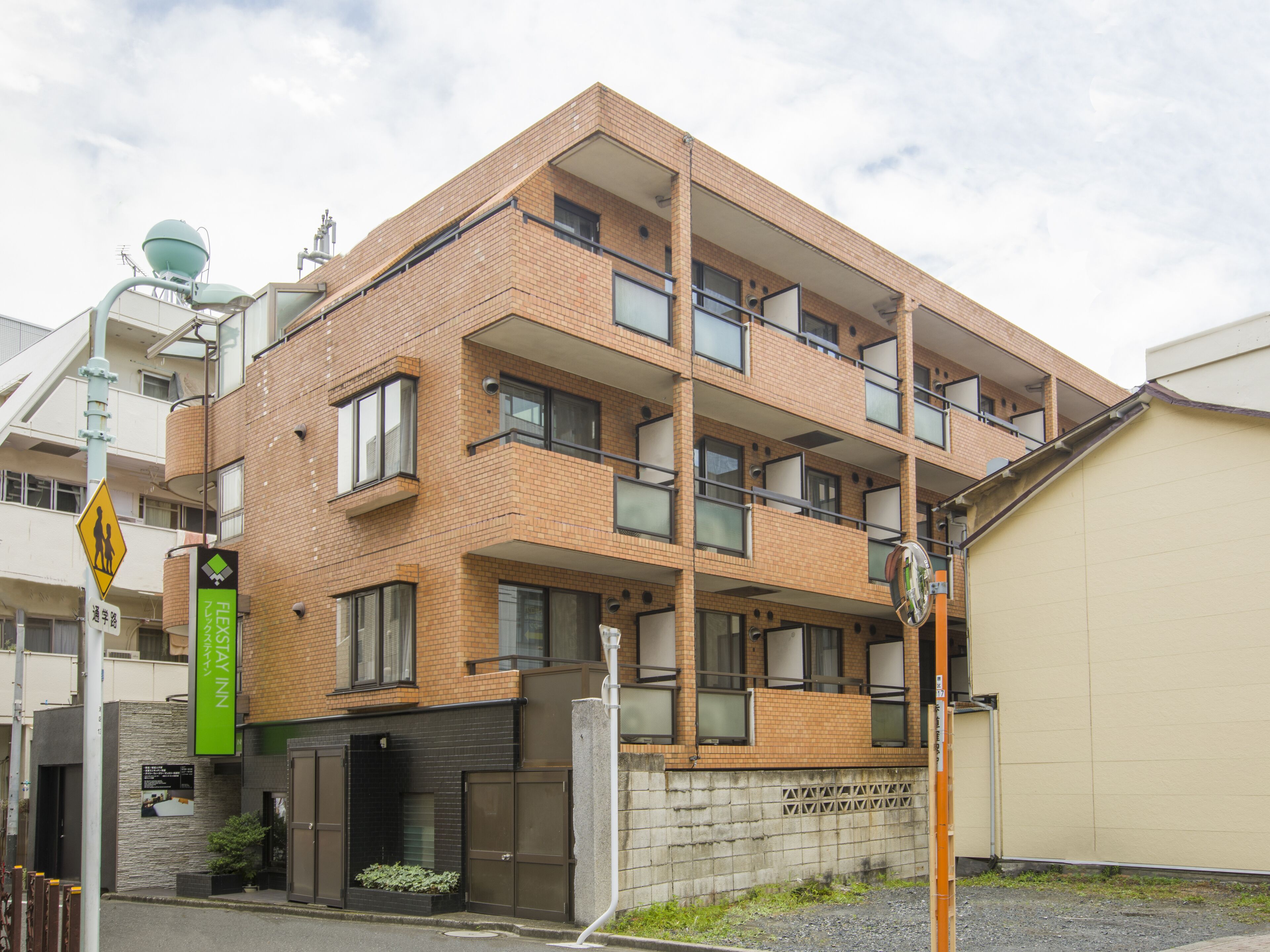 A multi-story building with a brick facade, multiple balconies, and a gated entrance.