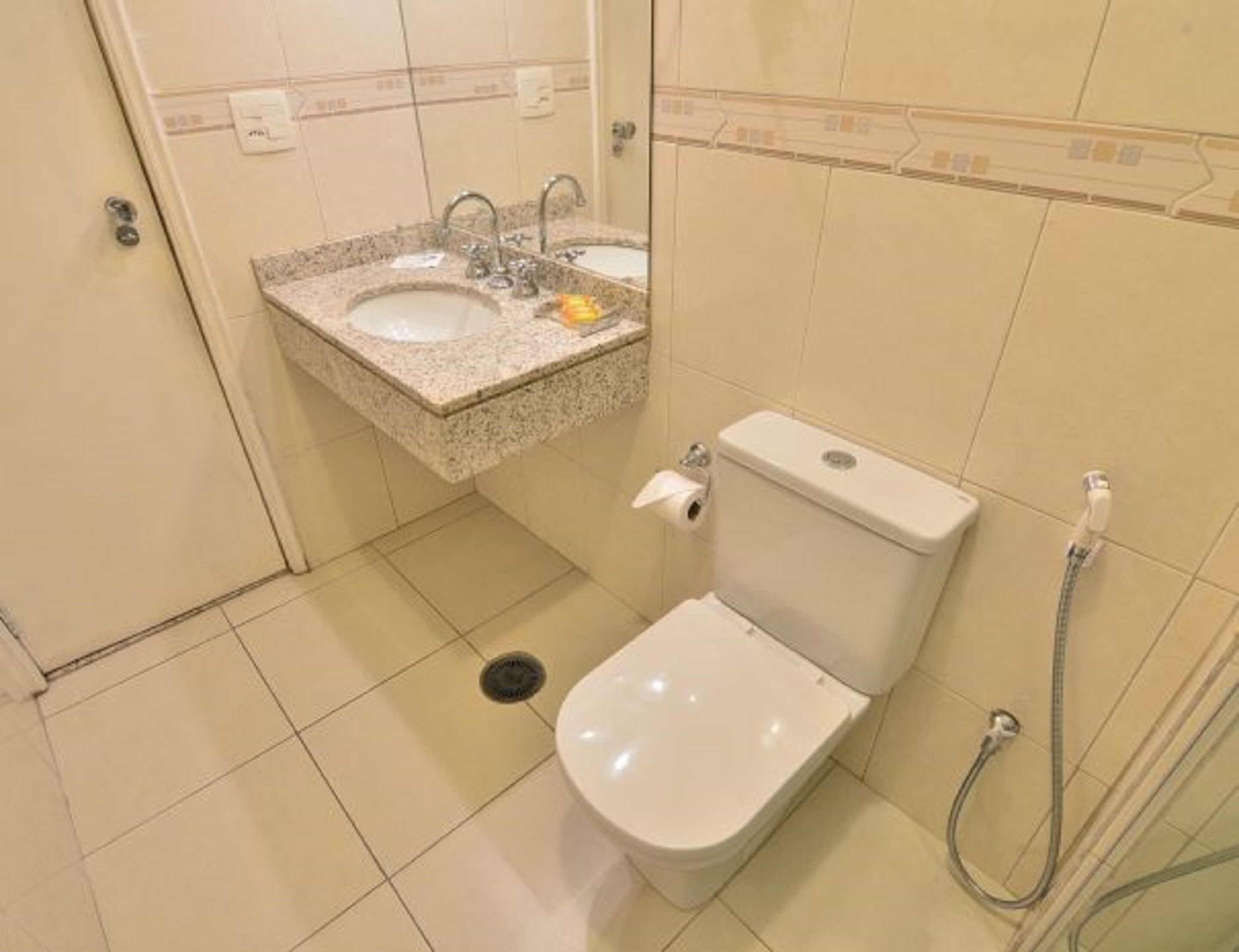 A bathroom with a toilet, two sinks, and a shower.