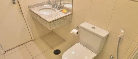 A bathroom with a toilet, two sinks, and a shower.