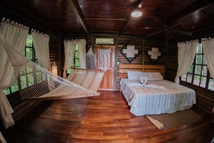 Una cabaña de madera con una cama, una hamaca y un ventilador de techo.