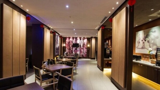 A modern restaurant interior with wooden paneling, tiled flooring, and a long counter with a television. - Jinjiang Inn (Beihai Beibuwan Square) (Beihai)