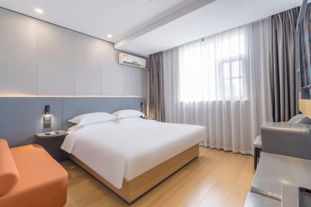 Una habitación de hotel moderna con una cama grande, una mesita de noche, una silla y un escritorio.