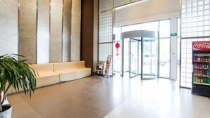 A lobby with a seating area, a revolving door, and a Coca-Cola refrigerator. - Jinjiang Inn (Beihai Beibuwan Square) (Beihai)