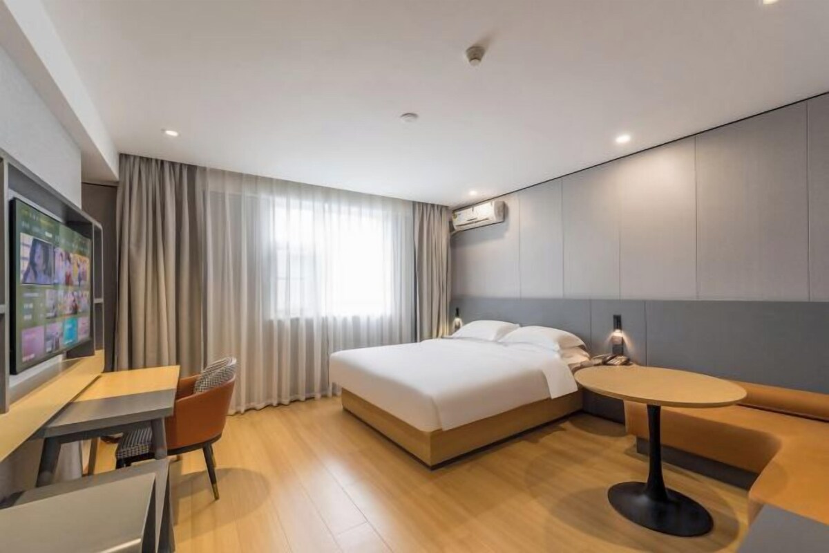 Una habitación de hotel con una cama, un escritorio, una silla, una mesa y un televisor.