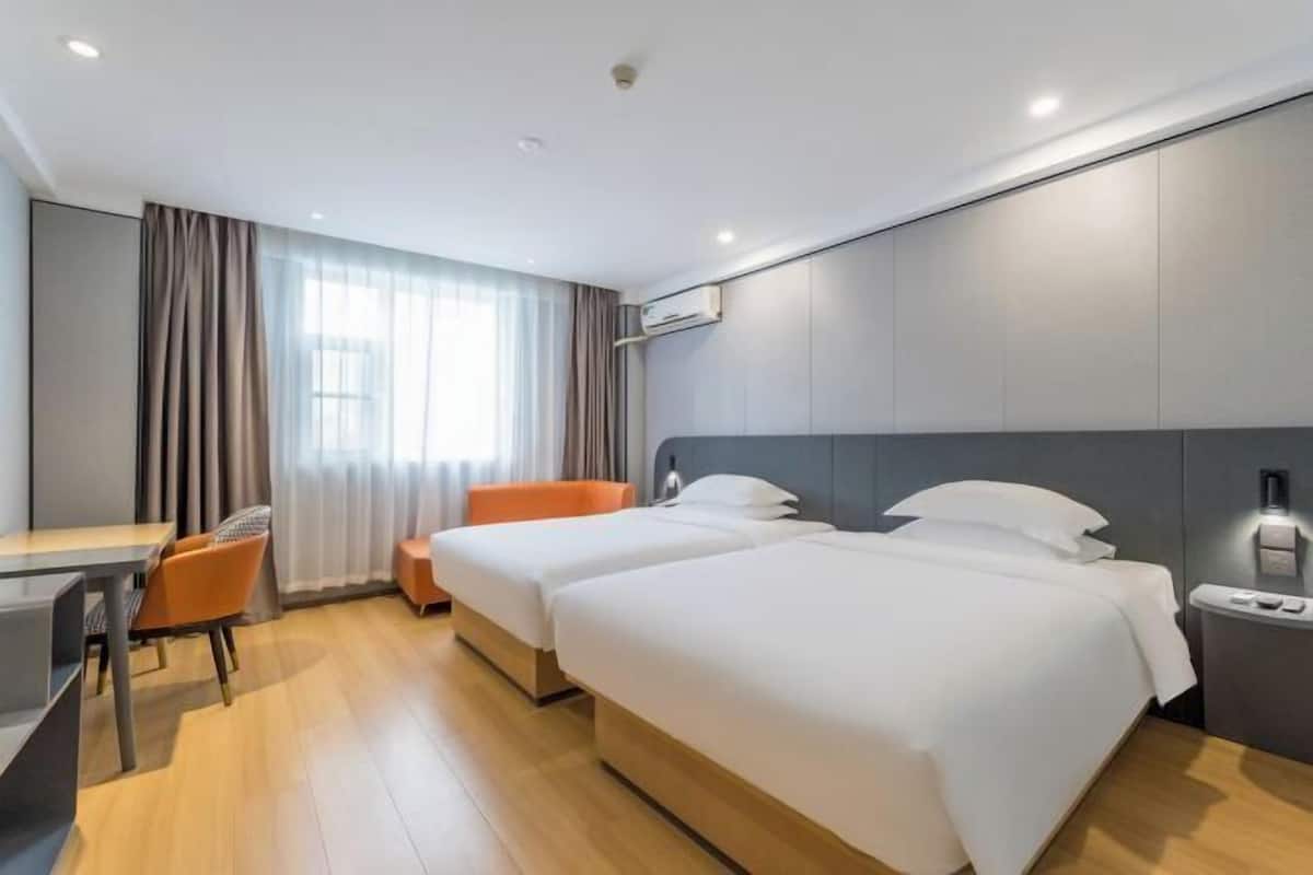 Een hotelkamer met twee bedden, een bureau en een stoel.