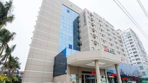 A multi-story hotel with a modern facade, featuring a prominent glass section and a covered entrance area. - Jinjiang Inn (Beihai Beibuwan Square) (Beihai)