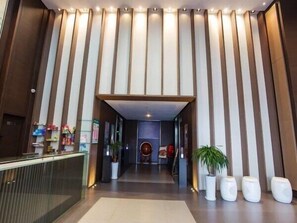A hotel lobby with a reception desk, a seating area, and a large vertical light panel.