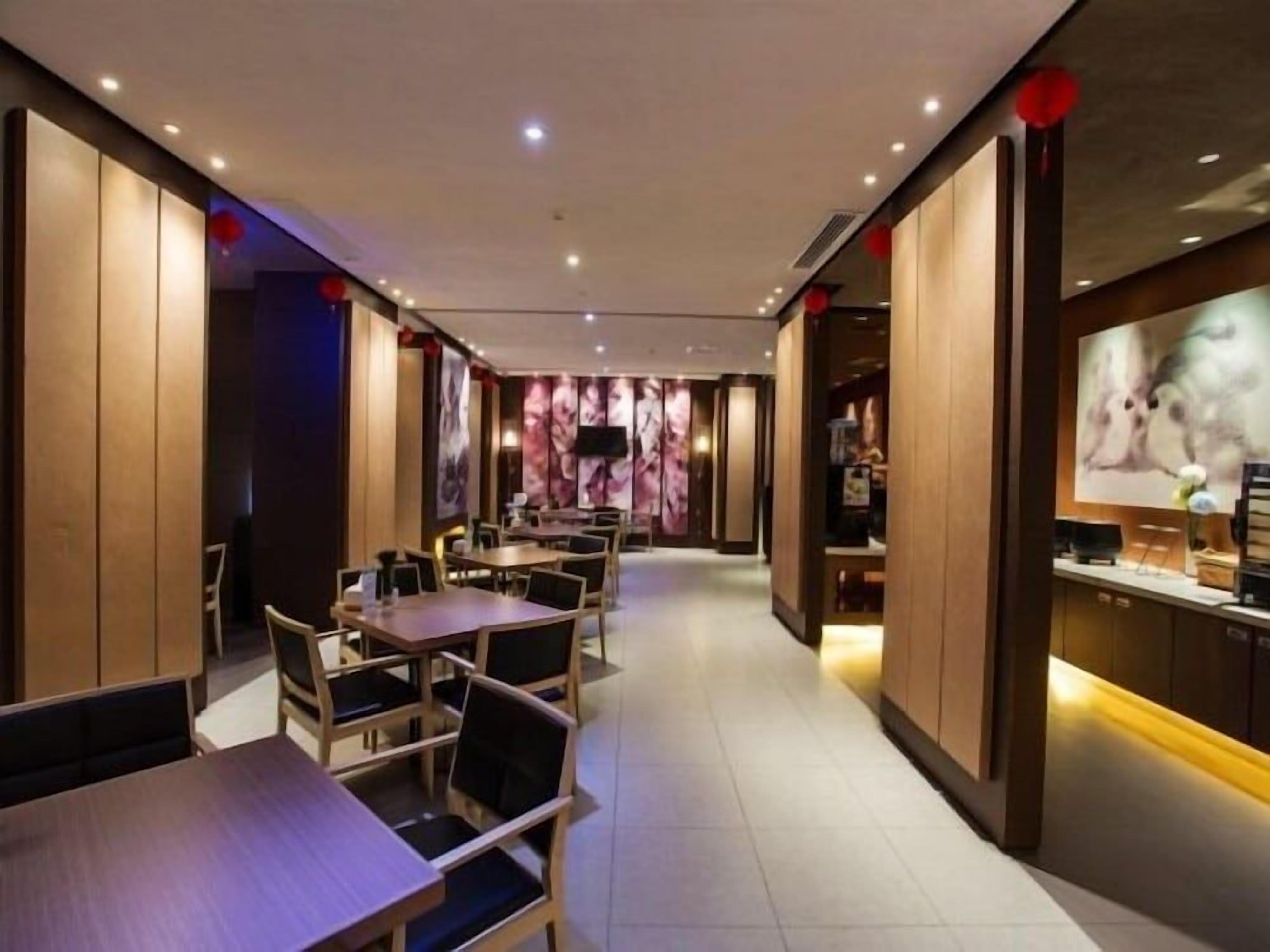 Interior de restaurante con paneles de madera, mesas, sillas y una pantalla de televisión.