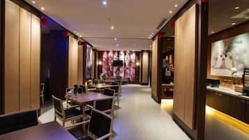 Interior de restaurante con paneles de madera, mesas, sillas y una pantalla de televisión.
