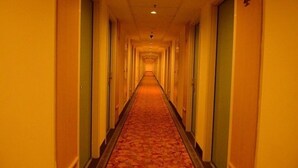 Un largo y estrecho pasillo de hotel con puertas a ambos lados y suelo cubierto de alfombra.