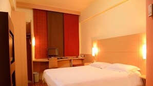 Habitación de hotel con una cama, un escritorio con ordenador y televisor.