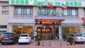 Un hotel con un letrero verde, varias ventanas y una bandera.